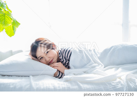 Smiling woman waking up in a good sleep in bed Smiling woman waking up in a good sleep in bed 97727130