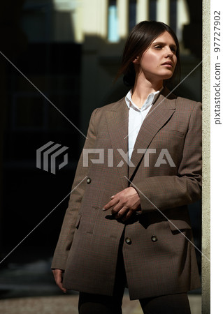 High fashion portrait of young elegant woman in brown suit walk on the street. enjoy summer lights. High fashion portrait of young elegant woman in brown suit walk on the street. enjoy summer lights. 97727902