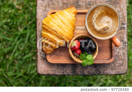 Coffee cup and croissant on outside garden table 97728380