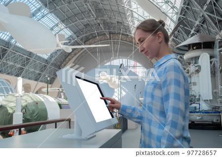Woman touching interactive white touchscreen display kiosk at exhibition 97728657