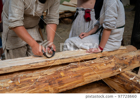 Man carpenter using drawknife to shape and smooth wood board Man carpenter using drawknife to shape and smooth wood board 97728660