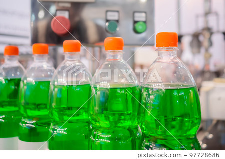 Row of pet bottles with green lemonade on conveyor belt - close up Row of pet bottles with green lemonade on conveyor belt - close up 97728686