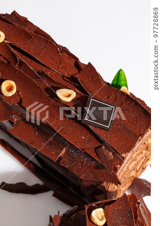 Festive Yule log with chocolate shavings, cocoa and hazelnuts Festive Yule log with chocolate shavings, cocoa and hazelnuts 97728869