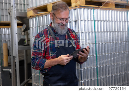 Man in plaid shirt working at the factory and looking busy Man in plaid shirt working at the factory and looking busy 97729164