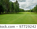 Golf course, landscape, green grass on the background of the forest and a bright sky with clouds. High quality photo 97729242