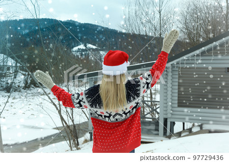 Woman in santa hat and Christmas sweater outdoor 97729436