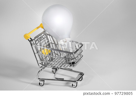 A burning light bulb in a shopping cart. A notion of energy saving A burning light bulb in a shopping cart. A notion of energy saving 97729805