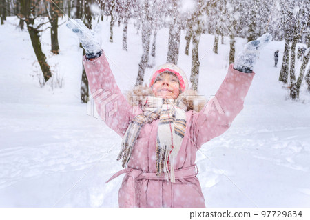A little girl is having fun playing with snow in the nature 97729834