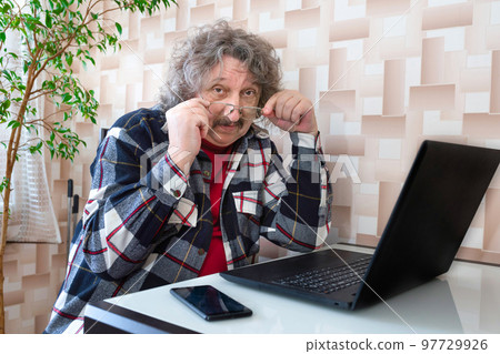 An elderly man in glasses working at the laptop An elderly man in glasses working at the laptop 97729926