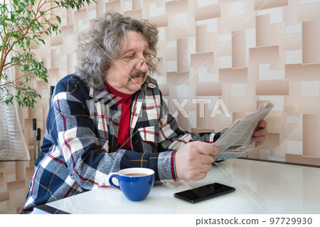 A portrait of a 60-year old man reading news. A newspaper in a pensioner's hands 97729930