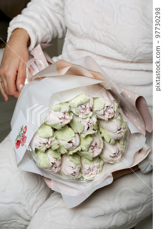 Marshmallow bouquet. Zephyr tulips. Natural homemade marshmallow. Packed in paper in the form of a bouquet. In the hands of a woman. Close-up. Marshmallow bouquet. Zephyr tulips. Natural homemade marshmallow. Packed in paper in the form of a bouquet. In the hands of a woman. Close-up. 97730298