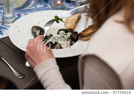 woman going to eat mussels in white wine sauce and white bread toasts in a restaurant woman going to eat mussels in white wine sauce and white bread toasts in a restaurant 97730810