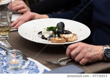 man going to eat mussels in white wine sauce and white bread toasts in a restaurant man going to eat mussels in white wine sauce and white bread toasts in a restaurant 97730815