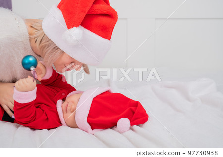 Caucasian woman hugging baby son in santa claus costume.  97730938