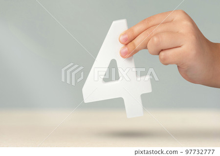 number four in hand. Hand holding white number 4 on blurred background with copy space. Concept with number four. Birthday 4 years, fourth grade, four day work week 97732777
