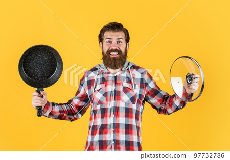 male hipster with fashionable groomed hair and beard cooking with pan, kitchen 97732786