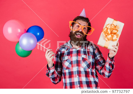 Big moment is coming. Multi colored fun. best party for retirement. cheerful man with beard hold present. hipster smiling with balloon. Celebrating happy party. Party Elements and holiday objects 97732797