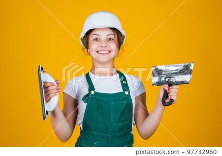 teen girl plasterer in protective helmet use spatula, plastering tool teen girl plasterer in protective helmet use spatula, plastering tool 97732960