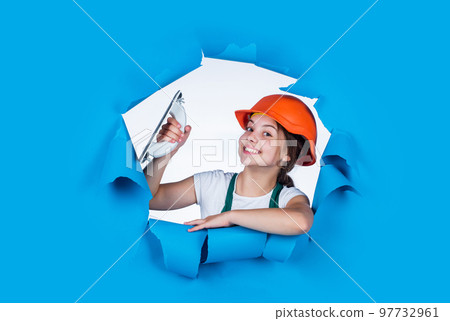 real happiness. young worker in protective hard hat. confident kid use spatula while repairing. concept of building and renovation. happy girl use spatula tool. teen builder wear safety helmet 97732961