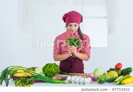 cheerful child girl cooking vitamin salad from vegetables, cuisine 97733032