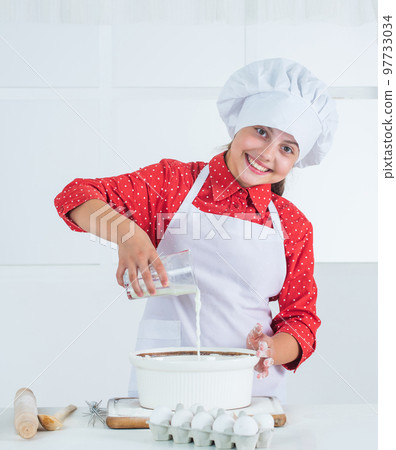 smiling teen girl in chef uniform cooking and baking, kitchen 97733034