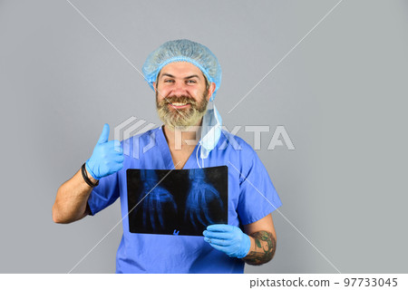 Hospital emergency. Doctor compares results. X ray radiation. Doctor holds pictures of bones. Fracture and bone damage. Doctor examines radiographic snapshot of wrist. Surgeon estimate damages 97733045