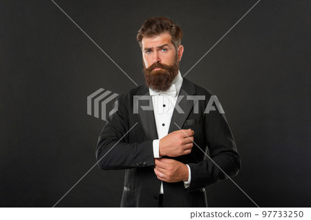 elegant butler in tuxedo on black background, suit 97733250