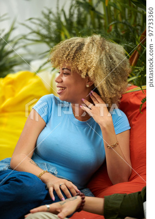 Portrait of young woman laughing at joke of friend at party 97733360
