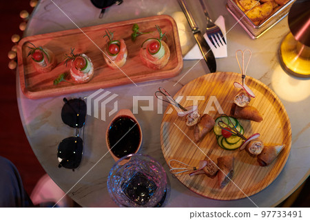 Wooden plates with tasty snacks on round table served for group of friends, view from above 97733491