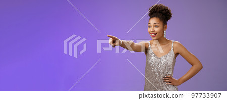 Impressed fascinated cute african-american woman excited pointing index finger sideways thrilled enjoying incredible exhibition standing excited blue background, glancing amused Impressed fascinated cute african-american woman excited pointing index finger sideways thrilled enjoying incredible exhibition standing excited blue background, glancing amused 97733907