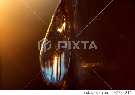Inverted sunset view and blue sky in a drop of pine resin 97734214