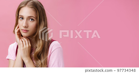 Woan feeling beautiful the way she is. Charming feminine and tender young girl with fair wavy natural hair and slight make-up touching face gently taking care of skin with organic cosmetics Woan feeling beautiful the way she is. Charming feminine and tender young girl with fair wavy natural hair and slight make-up touching face gently taking care of skin with organic cosmetics 97734348