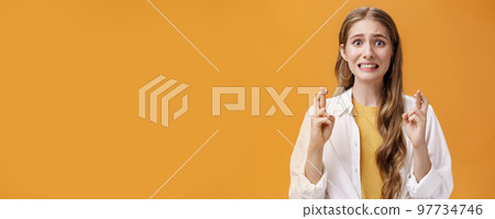 Girl hopes she did well on exam clenching teeth looking worried and concerned, crossing fingers for good luck praying making wish for dream come true waiting with expactation of miracle 97734746