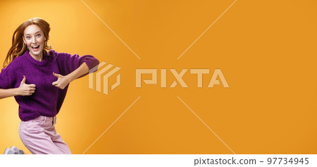 Excited and happy funny young redhead female in purple sweater jumping from happiness and satisfacion showing thumbs up gesture in approval giving positive reply and liking awesome clothes Excited and happy funny young redhead female in purple sweater jumping from happiness and satisfacion showing thumbs up gesture in approval giving positive reply and liking awesome clothes 97734945