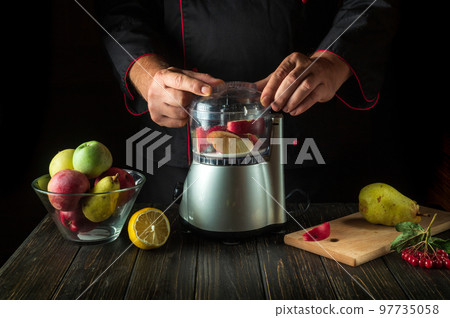 Professional chef prepares sweet fruit drink in a blender or mixer. Menu or recipe idea for a healthy vegetarian breakfast or dinner 97735058