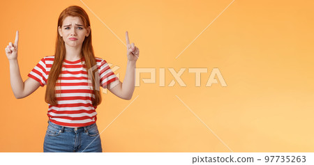 Disappointed upset cute whining timid redhead girl, gloomy face, pulling sad expression, complain, crying feeling regret loss, losing lottery, pointing up displeased, show despair and sorrow emotion 97735263