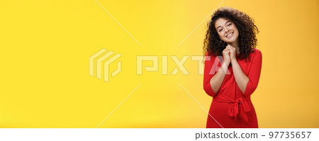 So sweet love you. Portrait of tender and silly cute curly-haired young woman in red dress tilting head holding hands together near face and smiling touched during heartwarming moment of confession So sweet love you. Portrait of tender and silly cute curly-haired young woman in red dress tilting head holding hands together near face and smiling touched during heartwarming moment of confession 97735657
