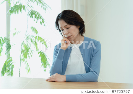 Middle-aged woman thinking in the living room 97735797