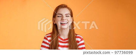 Sincere happy charismatic redhead girl smiling, close eyes enjoy warm summer sunbeams, laughing cheerful, feel relaxed rejoicing, show white teeth, good vacation concept, orange background 97736099
