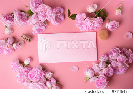 pink roses with white envelope and macaroons around pink background. life style concept pink roses with white envelope and macaroons around pink background. life style concept 97736454