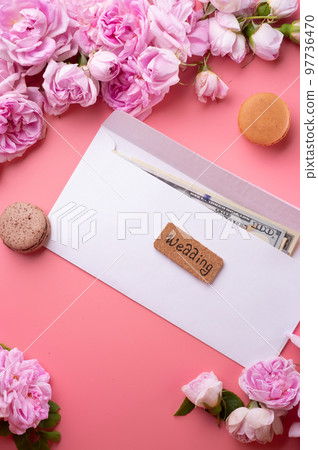 white envelope with cash around roses and macaroons against  pink background. life style concept 97736470