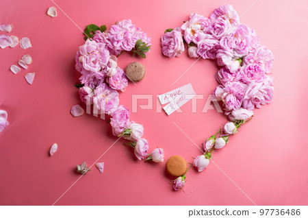 pink fresh fragrance roses in heart shape with macaroon around pink background. romantic and beauty concept pink fresh fragrance roses in heart shape with macaroon around pink background. romantic and beauty concept 97736486