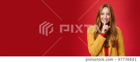 Shh keep it secret. Flirty and gentle attractive ginger girl with freckles teeling mysterious things showing shush gesture with index finger on mouth, smiling having surprise over red background Shh keep it secret. Flirty and gentle attractive ginger girl with freckles teeling mysterious things showing shush gesture with index finger on mouth, smiling having surprise over red background 97736681