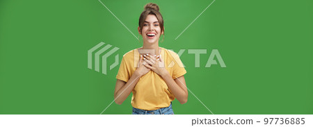 Delighted charming woman with gapped teeth in cozy outfit holding palms on chest in grateful or thankful pose smiling broadly receiving warm congratulations standing satisfied, happy over green wall Delighted charming woman with gapped teeth in cozy outfit holding palms on chest in grateful or thankful pose smiling broadly receiving warm congratulations standing satisfied, happy over green wall 97736885
