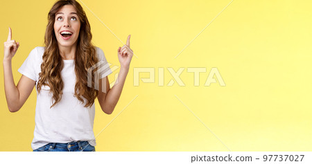 Happy impressed attractive girl long curly haircut drop jaw amused smiling surprised delighted look pointing up index fingers stare admiration fascinated awesome promo offer yellow background Happy impressed attractive girl long curly haircut drop jaw amused smiling surprised delighted look pointing up index fingers stare admiration fascinated awesome promo offer yellow background 97737027