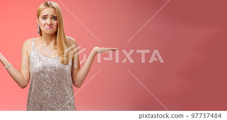 Upset clueless frustrated blond european young girl in glittering silver evening dress grimacing pouting sad shrugging raise hands sideways dismay doubtful, no idea what do, complicated decision 97737484