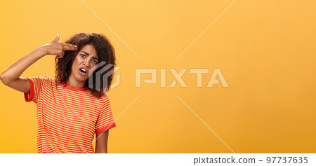 I would rather kill myself. Displeased bored and dissatisfied attractive bothered girlfriend in striped t-shirt tilting head, grimacing from dislike putting finger gun to forehead, commiting suicide 97737635