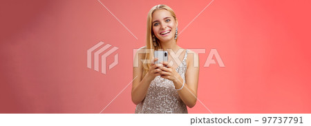 Charming elegant young 25s woman in silver dress brilliant accessorize holding smartphone messaging using app order taxi after nightclub friends party standing carefree smiling camera joyfully Charming elegant young 25s woman in silver dress brilliant accessorize holding smartphone messaging using app order taxi after nightclub friends party standing carefree smiling camera joyfully 97737791