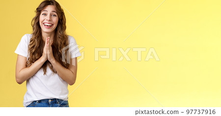 Cheerful cute hopeful girl clingy begging look camera optimistic faithfully press palms together pray supplication gesture asking favour pleading apology positive lucky mood yellow background 97737916
