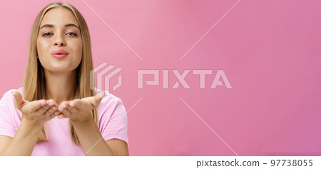 Spreading love to world. Portrait of charming sensual and tender romantic girlfriend holding palms over chest folding lips raising head and sending air kiss at camera with passion and romance 97738055